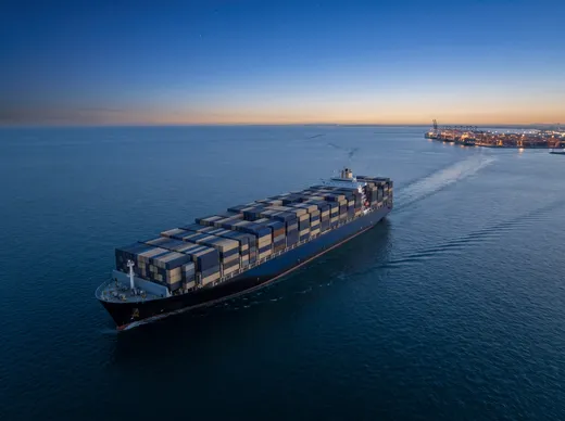 Importación marítima a Ecuador Buque portacontenedores navegando hacia el puerto al atardecer con carga de importación marítima